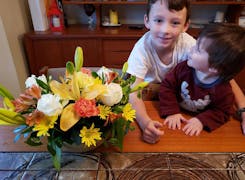 Two aspiring young floral designers, children of a staff member, proudly display their own small floral arrangement