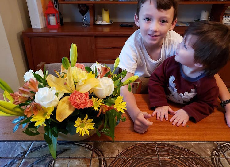 Two aspiring young floral designers, children of a staff member, proudly display their own small floral arrangement